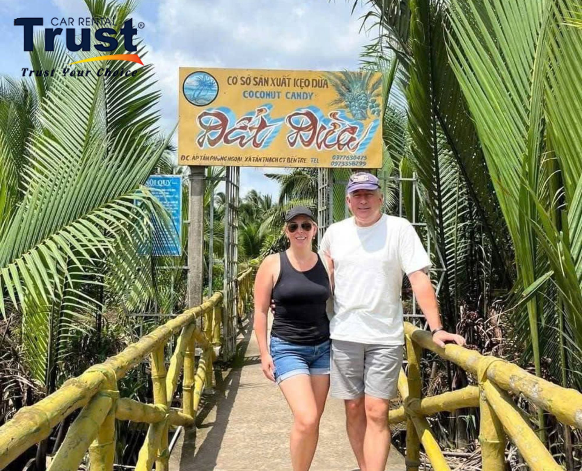 A couple takes a photo in front of a coconut candy facility in the Mekong Delta