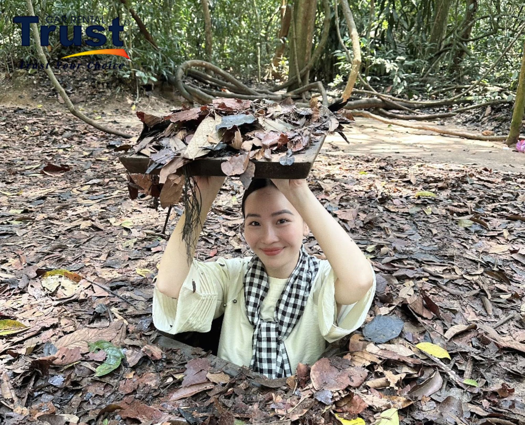 A person emerging from a camouflaged tunnel entrance at the Cu Chi Tunnels